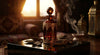 An ornate amber perfume bottle surrounded by raw agarwood chips and rising smoke, lit with warm golden light against a dark obsidian surface.